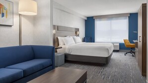 Ett hotellrum med en säng, en blå soffa, ett skrivbord och ett fönster med utsikt.