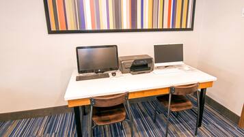 A workspace with two laptops, a printer, and a keyboard on a white table.