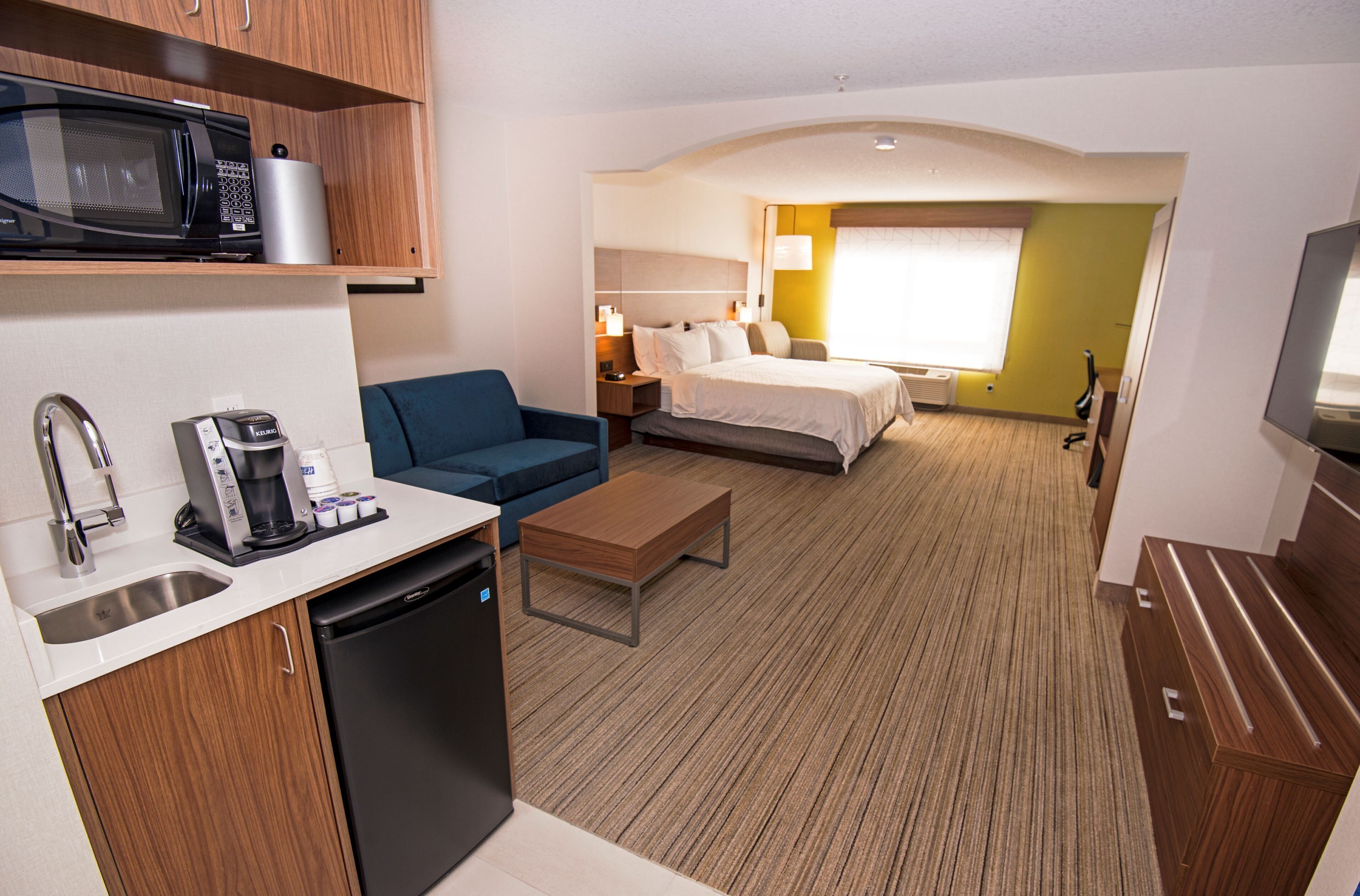 Een compacte hotelkamer met kitchenette, een bed, zithoek en televisie.