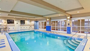 Une piscine intérieure à l’eau claire, avec des murs carrelés et des panneaux de signalisation de sécurité.