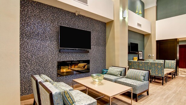 Un espace de détente moderne avec un mur à motifs, un téléviseur à écran plat, des sièges confortables et un plancher en bois.