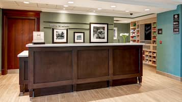 Una mesa de recepción con cuadros enmarcados, un cartel que dice "Welcome to London" y un letrero en la pared que dice "Treat Yourself".
