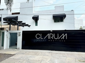 A modern hotel entrance with a black gate labeled "CLARUM HOTEL BOUTIQUE".