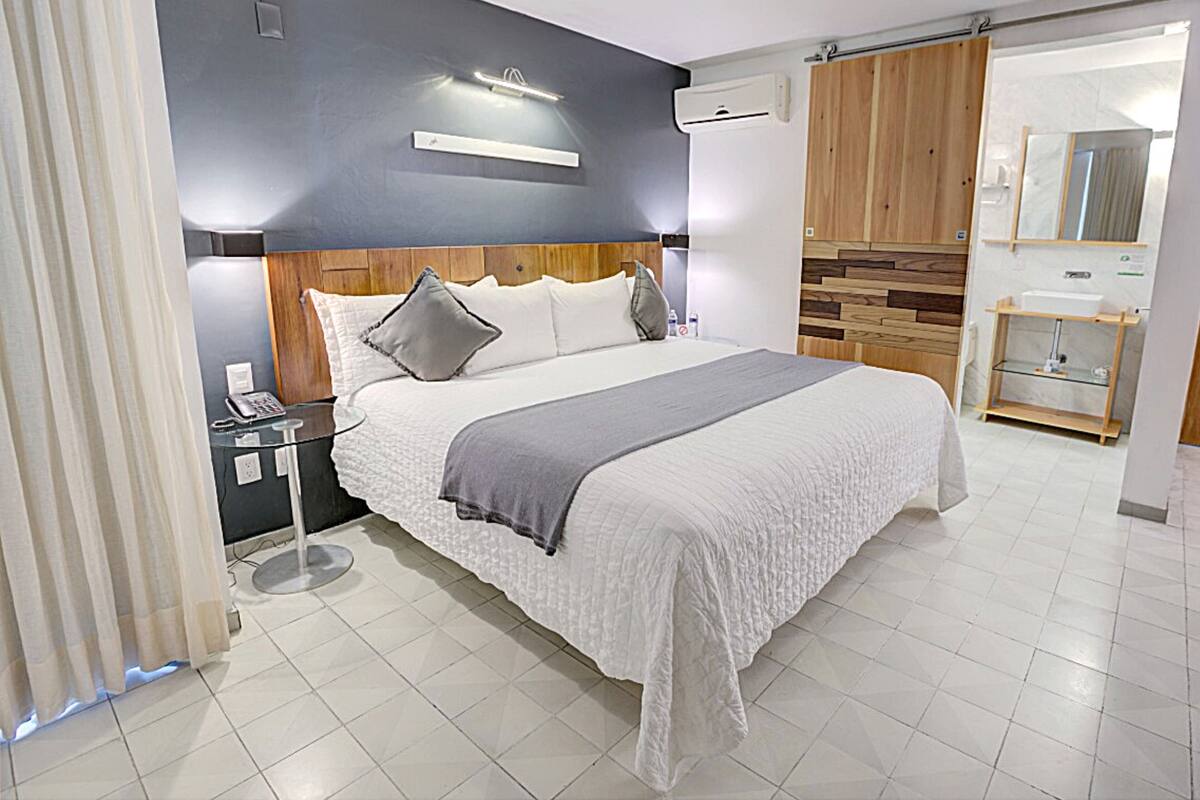 A modern hotel room with a large bed, bedside table, and a built-in wardrobe.