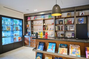 Una librería con estanterías llenas de libros, un mostrador con material promocional y una lámpara colgante.