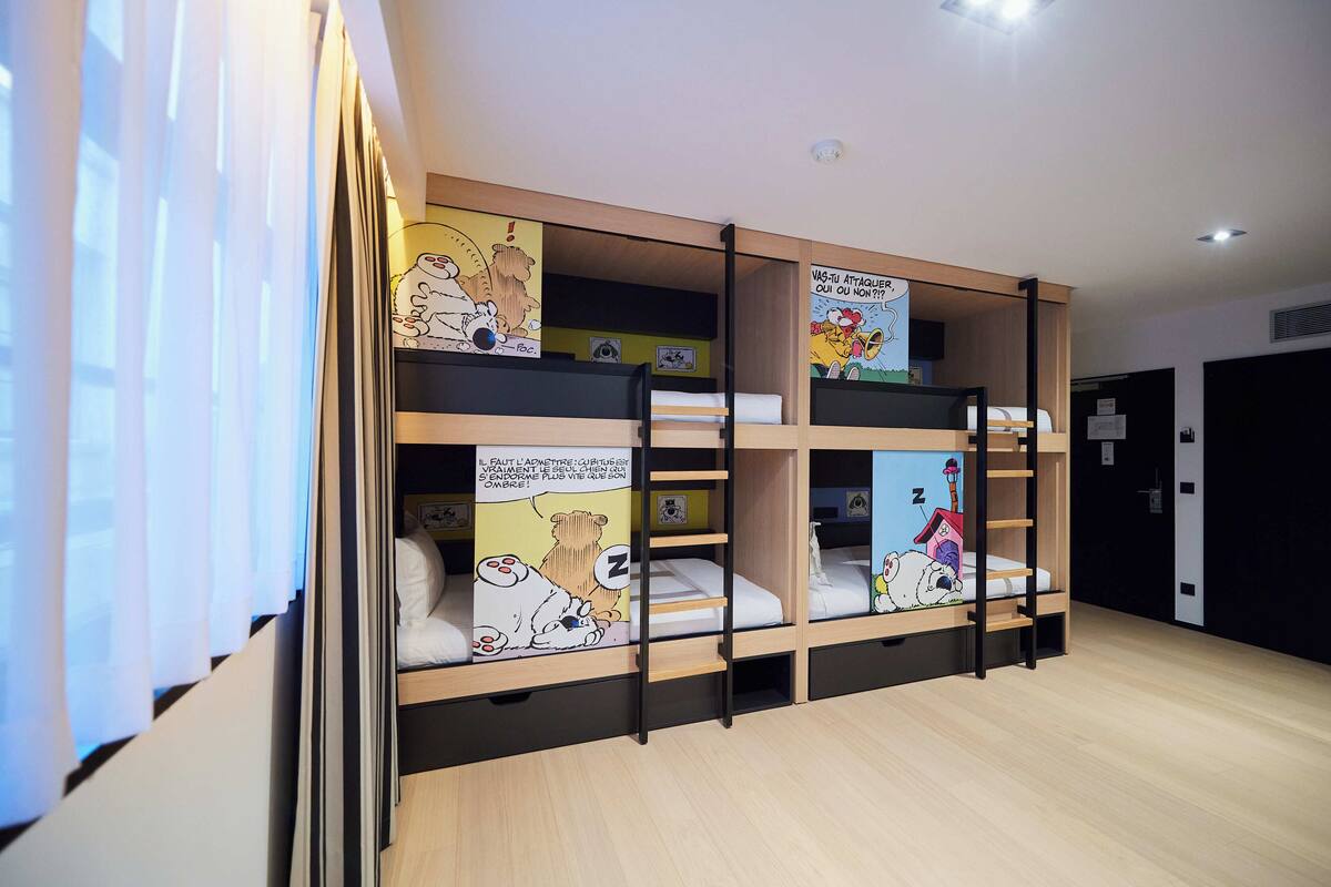 A multi-level bunk bed room with cartoon posters on the walls and a ladder for access.