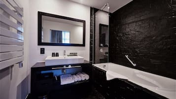 Casa de banho moderna com um espelho grande, uma banheira branca e uma parede de mármore preto.