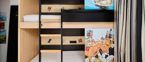 A bunk bed with a wooden frame, a lower shelf with a picture, and a mural on the wall.