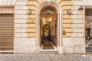 An entrance with a tiled floor leading to a hallway, flanked by two doors with numbers 12 and 13. - Hotel Artorius (Rome)