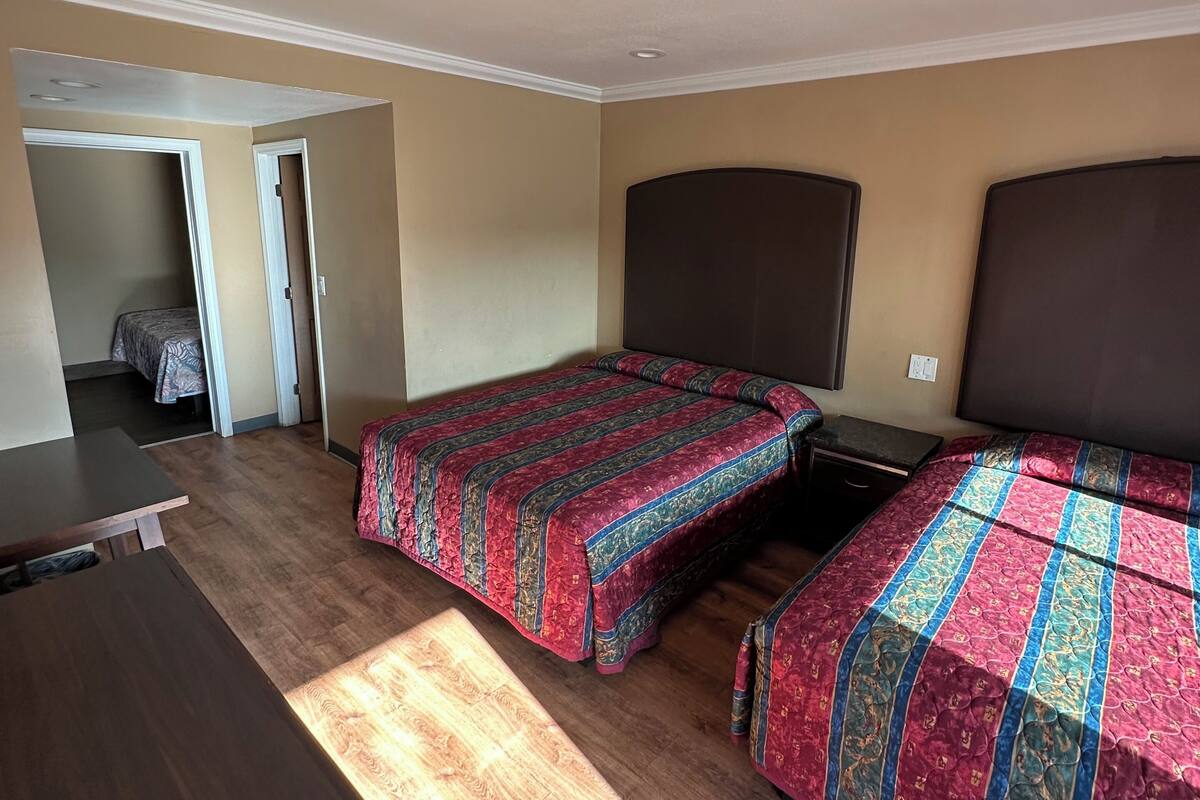 A bedroom with two beds, a wooden floor, and a dark headboard.