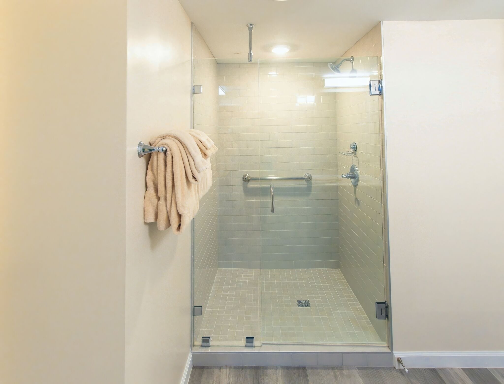 A walk-in shower with glass doors, a towel rack, and a tiled floor.