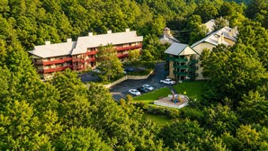 Eine Lodge mit mehreren Gebäuden, umgeben von dichtem Wald, einem Parkplatz und einem Spielplatz.