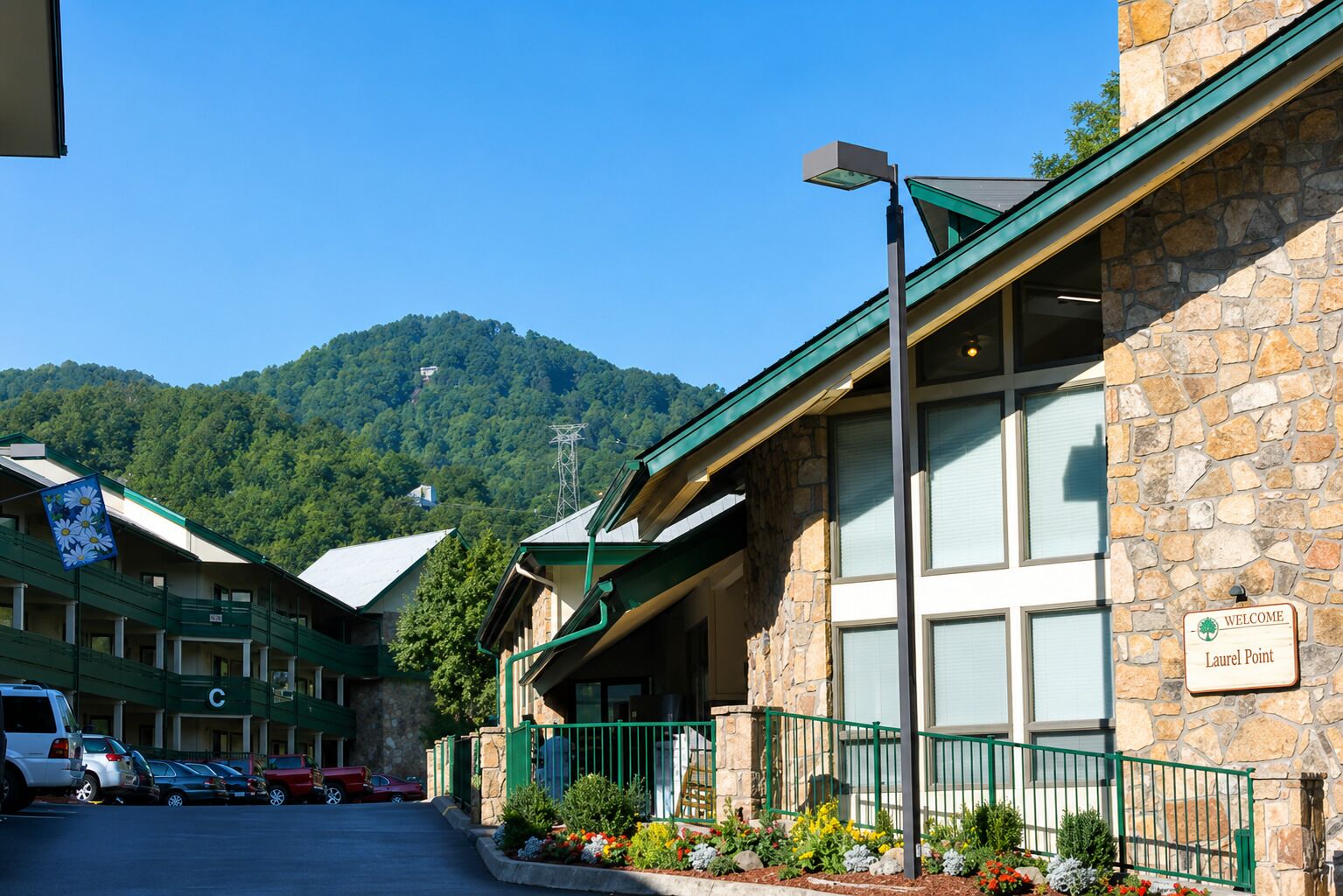 A hotel with stone exterior walls, a green roof, and a sign reading 'Welcome Laurel Point.'