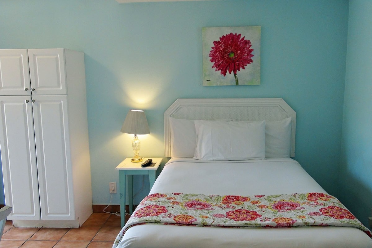 A bedroom with a bed, a nightstand, a lamp, and a wardrobe.