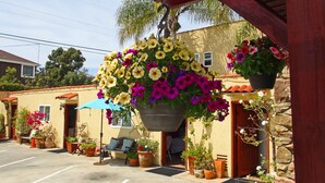 Un edificio con una maceta colgante, mesas al aire libre y plantas en macetas.