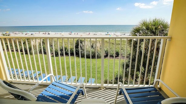 Ein Balkon mit blauen Liegestühlen und Blick auf den Strand.