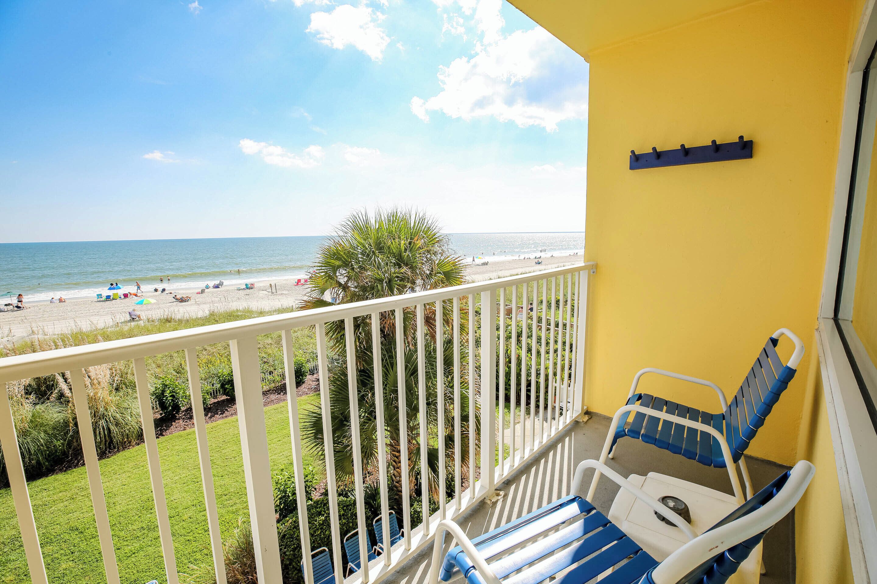 Ein Balkon mit Blick auf den Strand, ausgestattet mit Geländer, einer Bank und einem an der Wand befestigten Haken.
