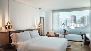 Ein modernes Hotelzimmer mit einem großen Bett, einem Schreibtisch und Blick auf die Stadtlandschaft.