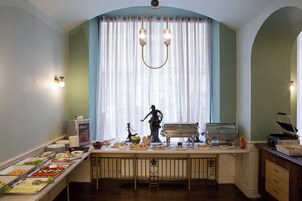A buffet setup with various food items, a statue, and a coffee station.