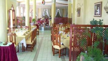 Een restaurant met houten tafels en stoelen, een betegelde vloer en een decoratieve scheidingswand met planten.