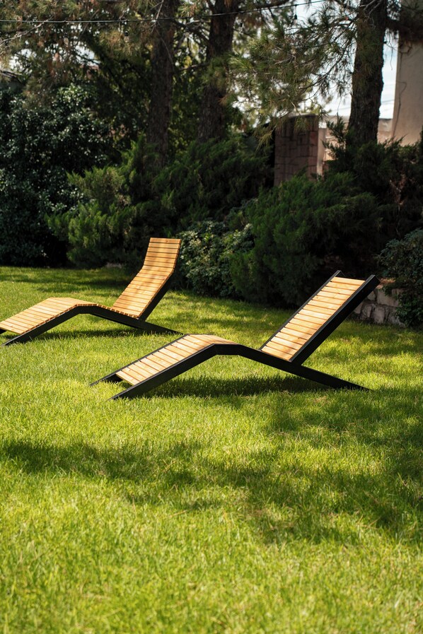 Two wooden lounge chairs on a grassy lawn with dense foliage in the background. - Victoria Express Durango (Durango)