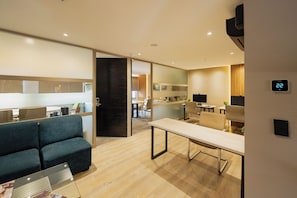A modern office space with a sofa, a long table, and a kitchen area.