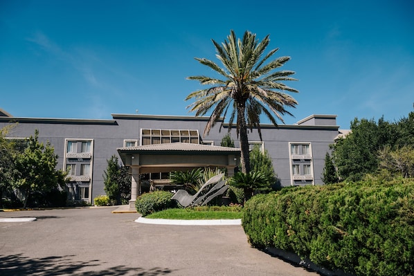 A modern building with a covered entrance, palm trees, and well-maintained landscaping.