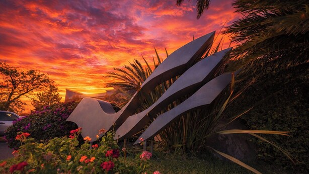 A sunset with vibrant colors, a modern sculpture, and lush greenery. - Victoria Express Durango (Durango)