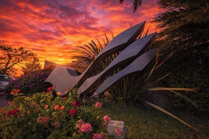 A sunset with vibrant colors, a modern sculpture, and lush greenery. - Victoria Express Durango (Durango)
