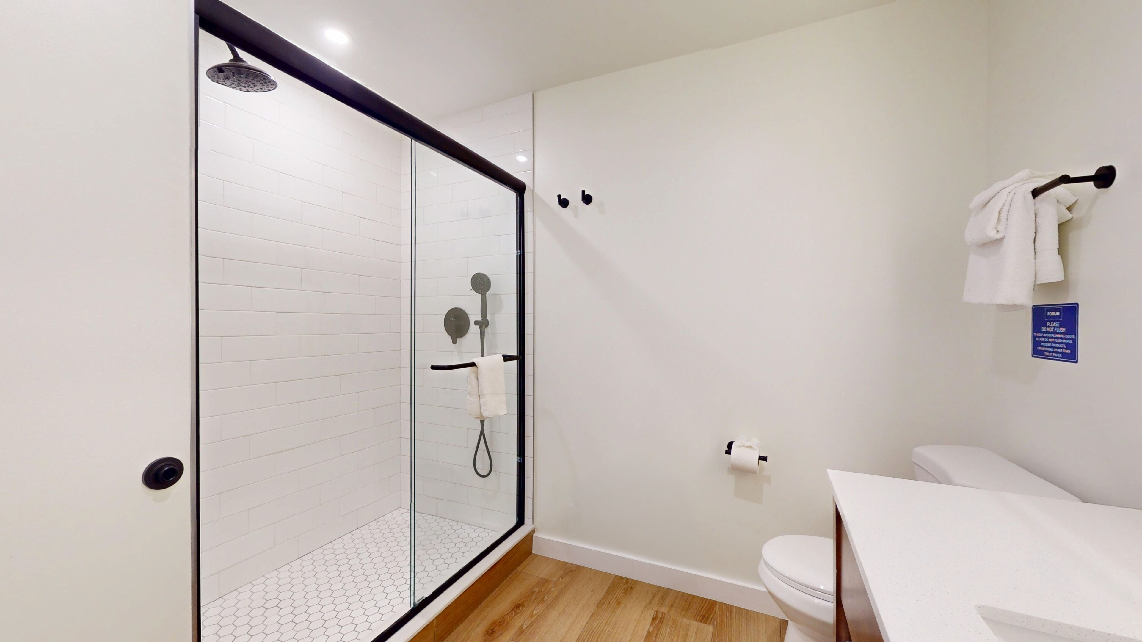 A modern bathroom with a glass-enclosed shower, a toilet, and a sink.