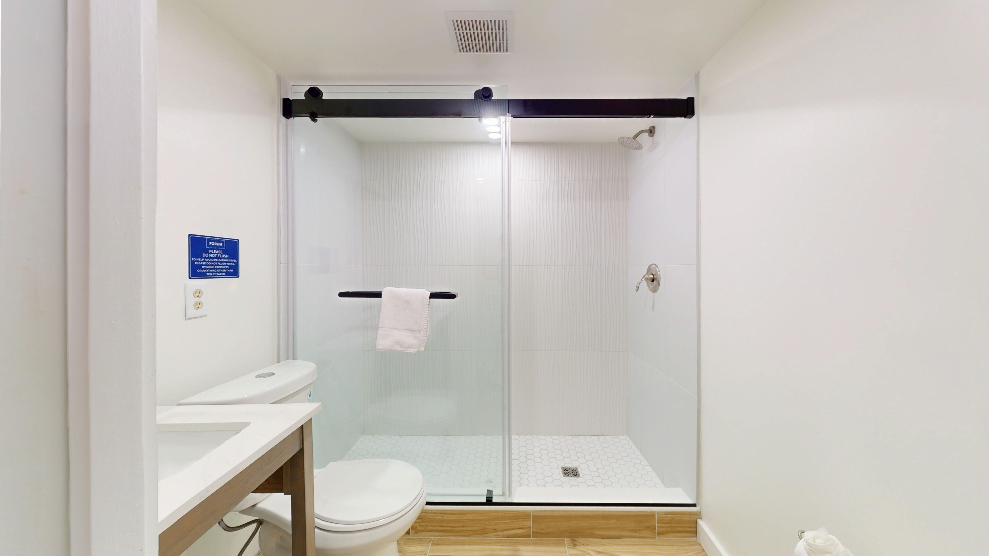 A modern bathroom with a glass-enclosed shower, a toilet, and a sink.