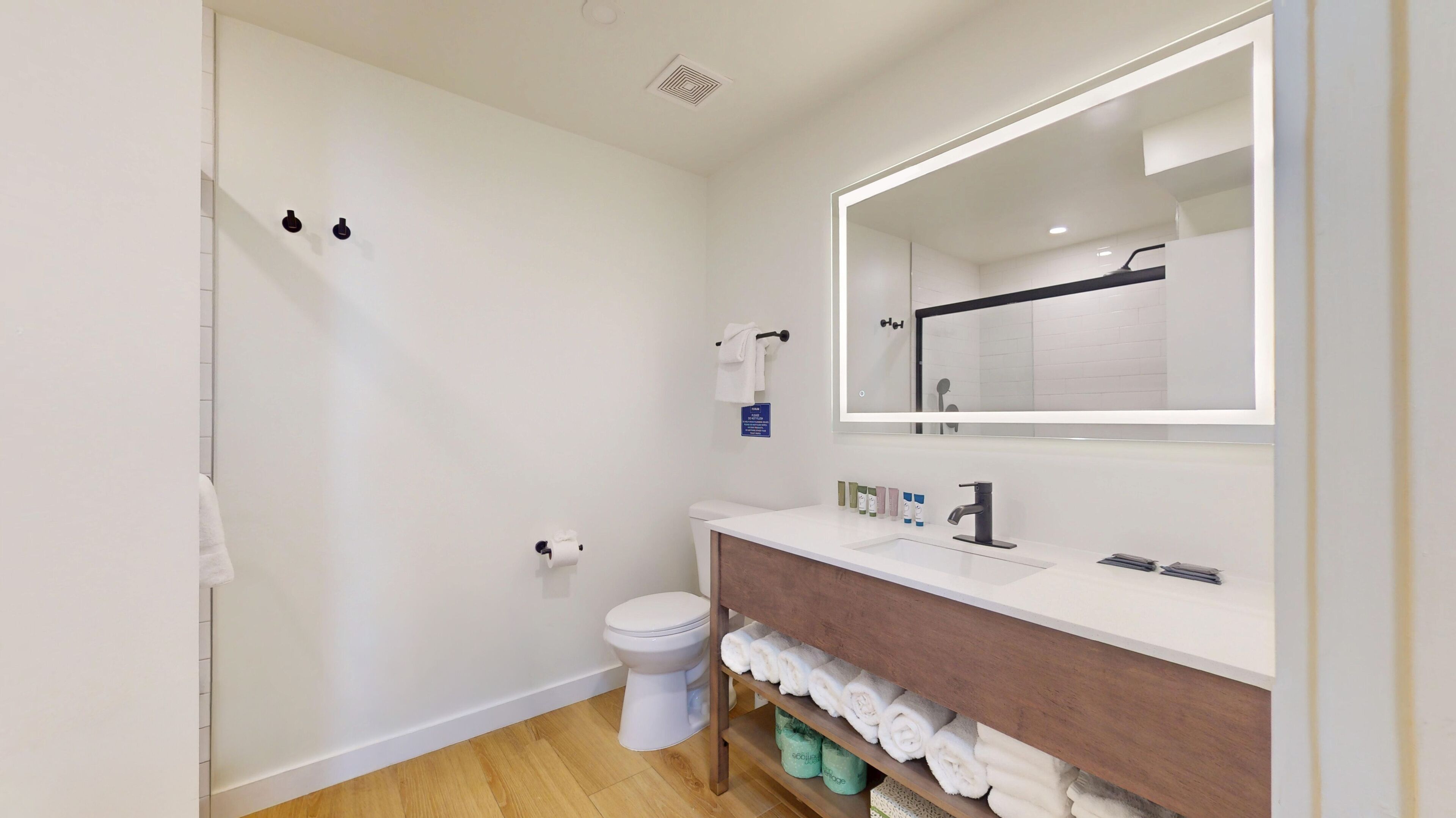 A modern bathroom with a white toilet, a sink with a mirror, and a towel rack.