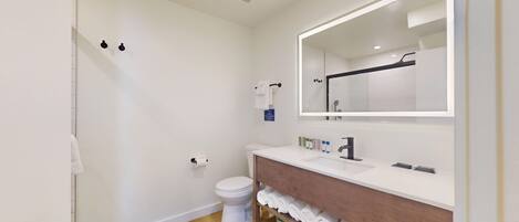 Een moderne badkamer met een wit toilet, een wastafel met spiegel en een handdoekrek.