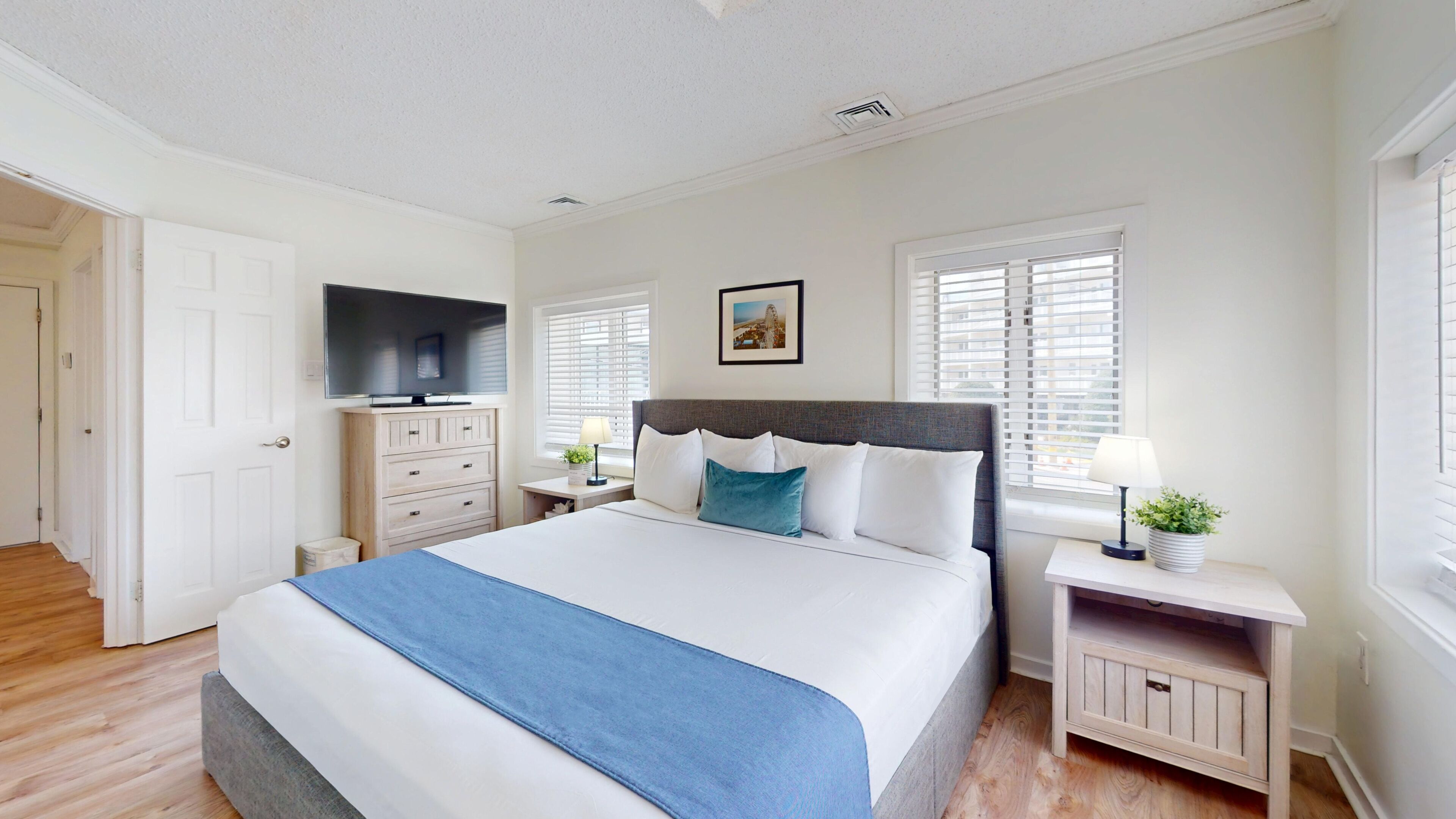 Un dormitorio con cama, cómoda, televisor y ventana con persianas.
