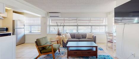 A modern living room with a sofa, armchair, coffee table, and a TV.