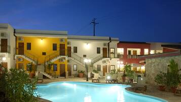 A swimming pool with a stone border, surrounded by potted plants and outdoor furniture.