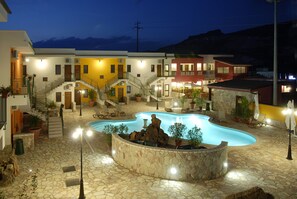 A hotel with a swimming pool, outdoor seating, and a mountainous backdrop. - Ciuri Di Badia (Buseto Palizzolo)