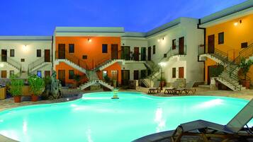 A swimming pool surrounded by multi-story buildings with balconies and staircases.