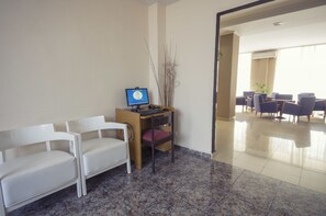 A reception area with a desk, computer, and two white chairs. - Azuline Hotel Mediterraneo (Santa Eulalia del Rio)