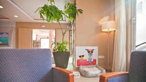 A hotel room with a large potted plant, a dog bed, and a painting of a dog on the wall. - Azuline Hotel Mediterraneo (Santa Eulalia del Rio)