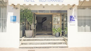The entrance to Hotel Mediterraneo with a clear view of the stairs leading inside, a blue sign with an 'H' indicating the hotel, and a large potted plant on the right. - Azuline Hotel Mediterraneo (Santa Eulalia del Rio)