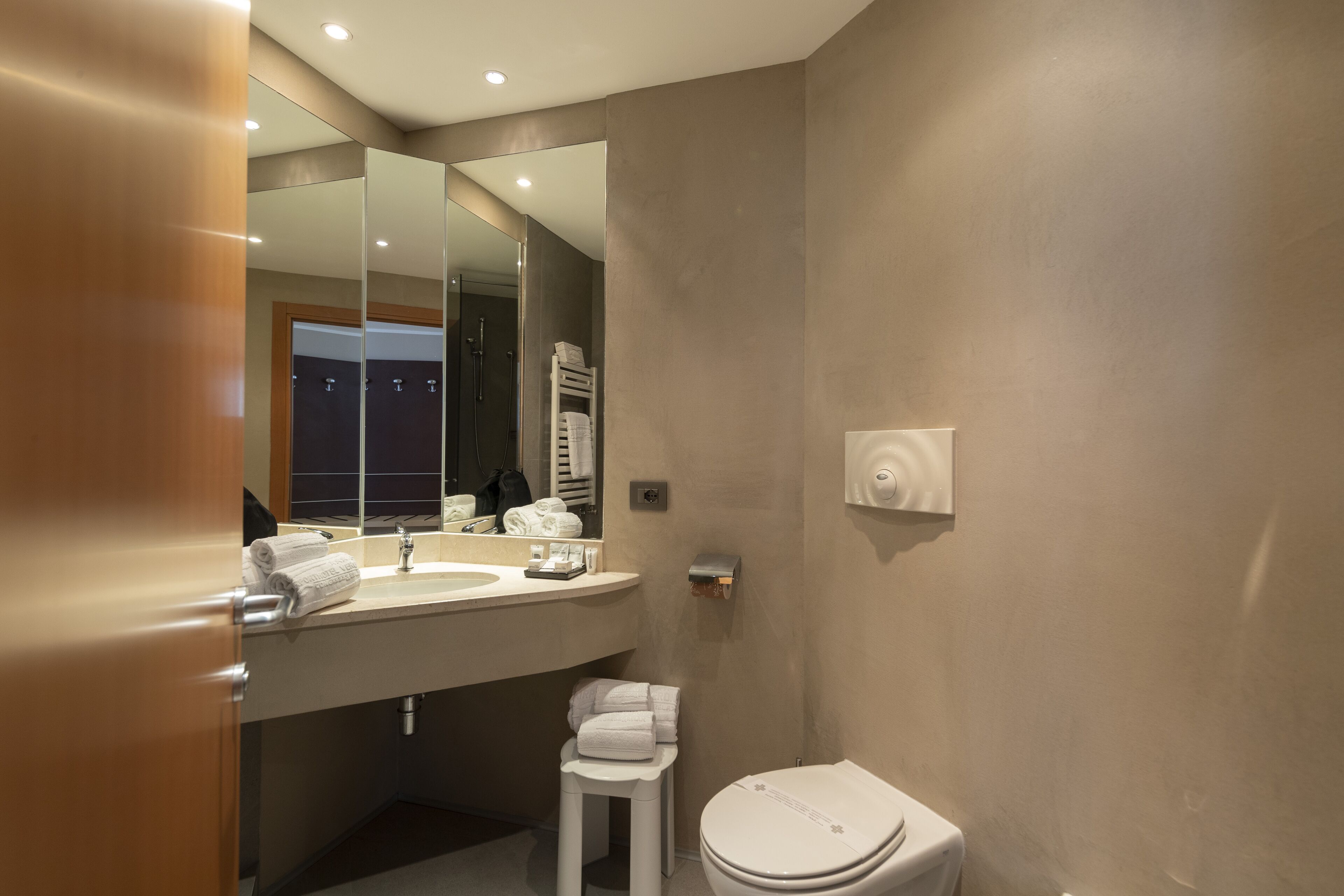 A modern bathroom with a large mirror, a sink, a toilet, and a towel rack.