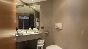 A modern bathroom with a large mirror, a sink, a toilet, and a towel rack.