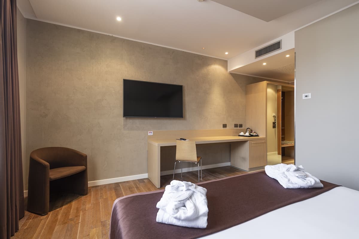Een hotelkamer met een bed, een bureau, een stoel en een televisie.