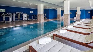 Uma área de piscina com equipamentos de ginástica e espreguiçadeiras.