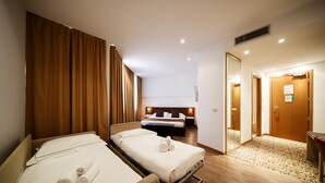 Quarto de hotel com duas camas de solteiro, chão de madeira e banheiro separado.