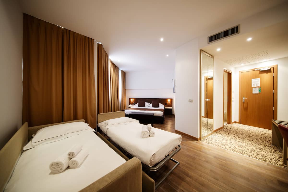 Een hotelkamer met twee eenpersoonsbedden, een houten vloer en een aparte badkamerruimte.