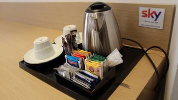 Ein Hotel-Rezeptionsbereich mit einer Kaffeemaschine, einer Platte mit verschiedenen Snacks und einem Schild, das den Sky Kamera Service anzeigt.