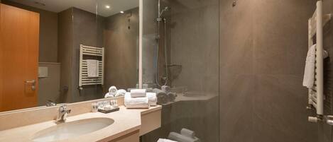 A modern bathroom with a large mirror, a sink, a shower, and a towel rack.