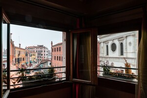 A window with a view of a cityscape, including buildings and a canal.